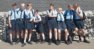 Gruppe Jungs, die keine kurzen Hosen tragen durften trotz heißer Temperaturen kämpft zurück, indem sie Röcke tragen