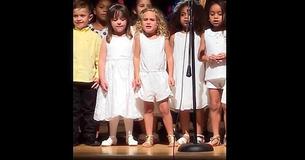 Vorschulkinder stehen für eine Musikvorführung bereit, als das kleine blonde Mädchen im Zentrum das Herz eines jeden stiehlt