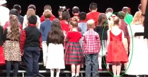 Les enfants s'alignent sur scène et au moment où ils se retournent, le public a les yeux rivés sur la petite fille en robe rouge