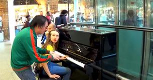Un homme en vert interrompt une jeune fille jouant du piano avec une mise en scène qui fait affluer la foule