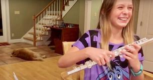 Une jeune fille essayent de faire de la flûte et son chien est hilarant
