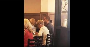 Une femme âgée au restaurant demande une table pour 1. Soudainement, un jeune homme se lève et montre du doigt un siège vide
