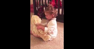 Babymeisje krijgt een beer van uitgezonden vader en straalt wanneer ze zijn hand pakt