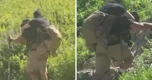 Des randonneurs regardent de plus près le sac à dos d'un homme et se rendent compte qu'il transporte l'un de ses camarades de la Marine qui a été blessé au combat