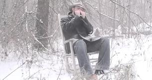 Un homme joue "Amazing Grace" à l'harmonica alors qu'il est assis seul dans la neige