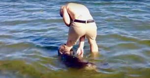 Un homme sur une plage canadienne joue avec une gentille loutre de mer qui tire sur sa jambe
