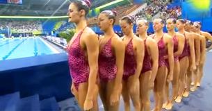 10 elegante Schwimmerinnen bilden eine Reihe, wobei die Frau ganz hinten die Aufmerksamkeit des Publikums auf sich zieht