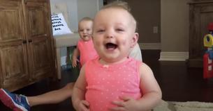 De baby doet eerste stapjes en valt voorover van het lachen
