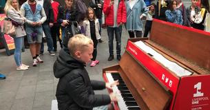 Un jeune garçon s'assoit sur un piano et joue un medley de quatre minutes de tubes qui rassemble une foule immense