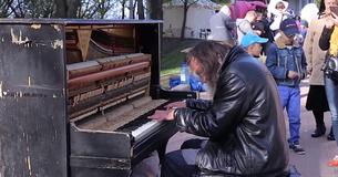 Un sans-abri s'assoit sur le trottoir devant un piano cassé. Les spectateurs s'approchent pour l'écouter