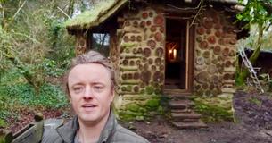 Un homme montre l'intérieur de sa petite maison située dans les bois