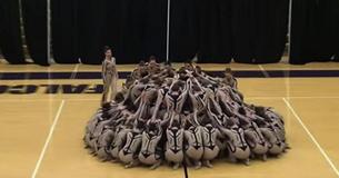 Un grand groupe de lycéens forme un cercle. Les spectateurs se concentrent sur la chorégraphie alors que les jambes des danseurs se séparent.