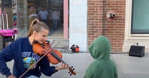 Un niño no puede evitar acercarse a una violinista y darle un beso durante su actuación callejera