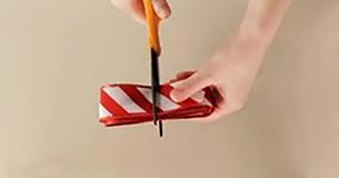 Sie schneidet die Rolle Geschenkband zur Hälfte durch für den besten Einpack-Trick überhaupt  